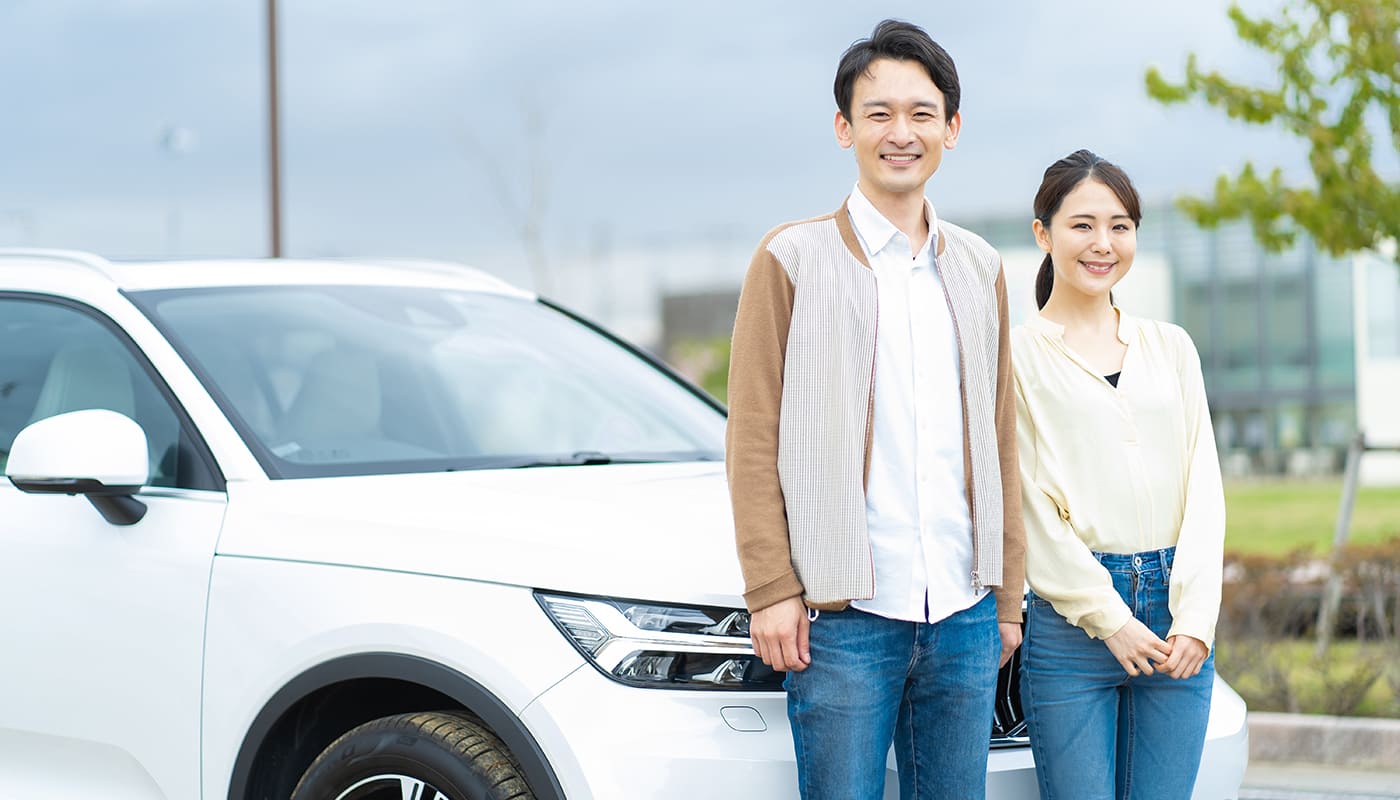 車の前で微笑む夫婦