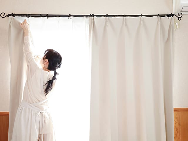 カーテンを取り付ける女性