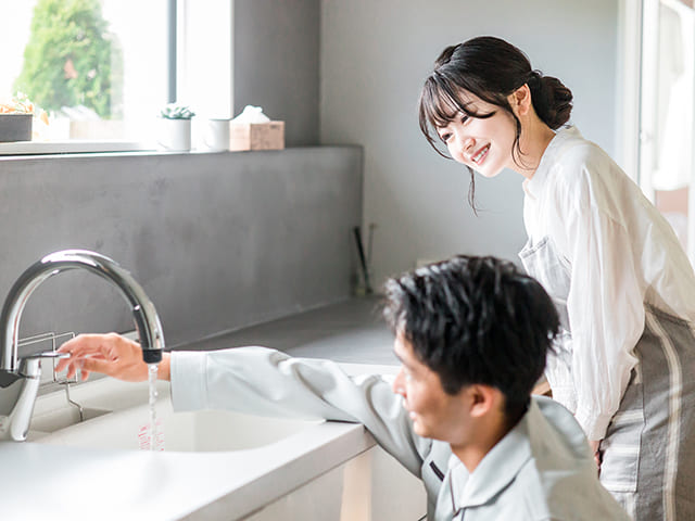 シンクの点検をする作業員と女性