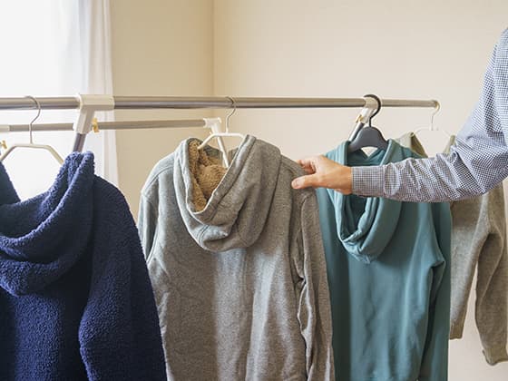 室内でパーカーを着ようとする男性