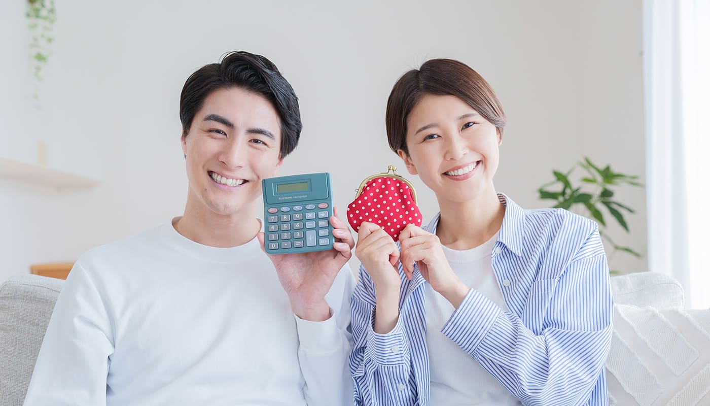 電卓と財布を持ってほほえむ夫婦